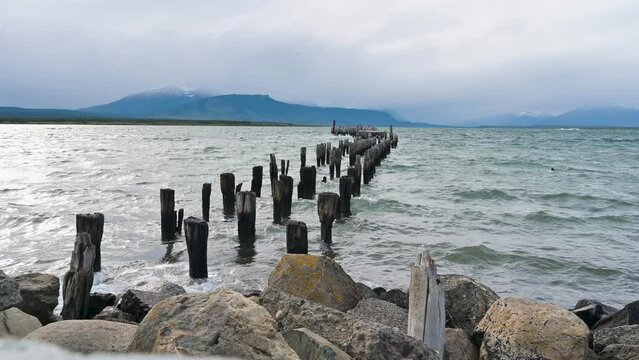 Footage of the old Puerto Natales pier with a black necked swan over the waves and mountains, Puerto Natales, Chilean Patagonia, Chile - stock video