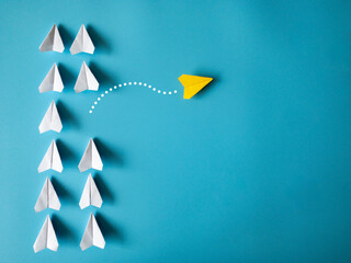 Yellow paper airplane origami leaving other white airplanes on blue background with customizable space for text. Leadership skills concept