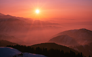 Magical atmosphere of a sunset evening in the highlands; mountain ranges and valleys shrouded in gentle mist at sunset