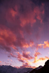 Bizarrely interesting sunset clouds over snow-capped mountain peaks