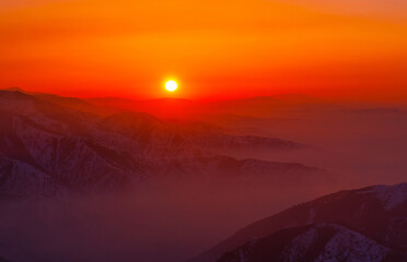 Magical atmosphere of a sunset evening in the highlands; mountain ranges and valleys shrouded in gentle mist at sunset