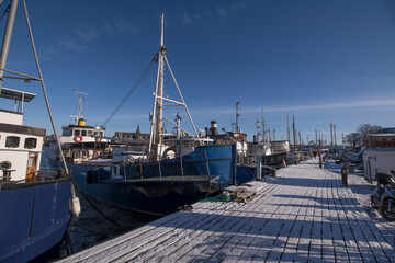 Moored fishing boats at a snowy wood pier a winter day in Stockholm