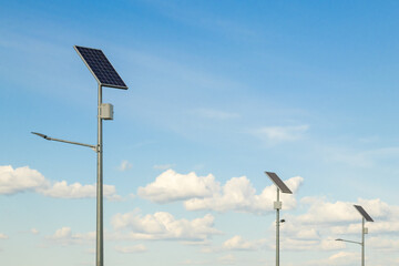 Solar device with street lamp on background of blue sky. Street light powered by solar panel with battery included. Alternative energy from the sun