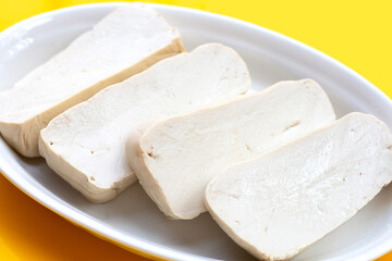 White tofu in white plate on yellow background.