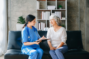 Medical doctor holing senior patient's hands and comforting her at home.