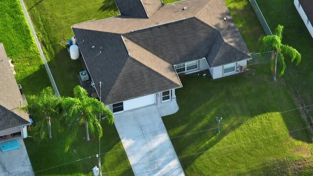 Aerial view of typical contemporary american private house with roof top covered with asphalt shingles and green lawn on yard