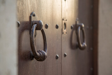 Old wooden doors with rings and old-fashioned vintage steel knocker handle close up in Italy.