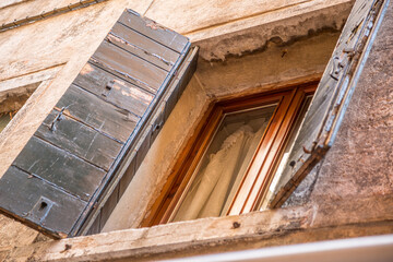 Window with brown shutters on the window sill in Italy.