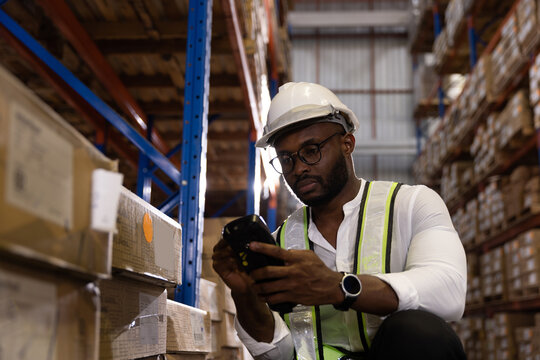 Black male staff using digital barcode scanner working checking stock in logistic warehouse