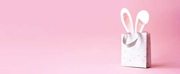 Easter bunny ears in a paper bag. Pink background. Space for text. Happy easter.