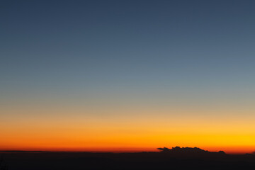 Fototapeta na wymiar Heaven at early morning with copy space. Sunset, sunrise backdrop.Predawn clear sky with orange horizon and blue atmosphere. Smooth orange blue gradient of dawn sky.