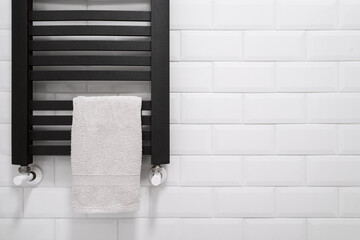 black heated towel rail in bathroom with white tile