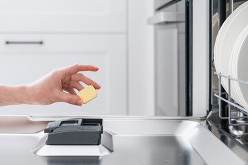 woman loading tablet into dishwasher with plates, closeup
