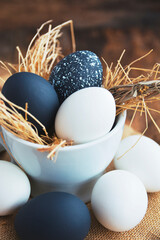 black and white colored Easter eggs in nest on wooden background, selective focus image. Happy Easter card