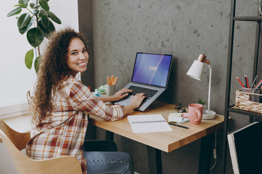 Side profile view young smart successful employee IT business woman of African American ethnicity wear casual shirt writing type password sign in on laptop pc computer sit work at office desk indoors. - Powered by Adobe