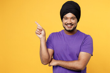 Smiling devotee Sikh Indian man ties his traditional turban dastar wear purple t-shirt point index...