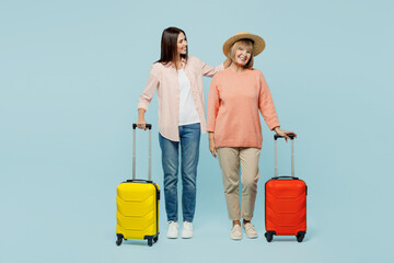 Elder parent mom with young adult daughter two women in casual clothes hat hold suitcase bag...