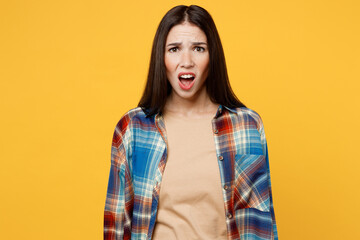 Young sad shocked indignant displeased caucasian woman wearing blue shirt beige t-shirt looking camera with opened mouth isolated on plain yellow background studio portrait. People lifestyle concept.