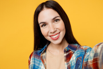 Fototapeta premium Close up young cheerful smiling caucasian woman wear blue shirt beige t-shirt doing selfie shot pov on mobile cell phone isolated on plain yellow background studio portrait. People lifestyle concept.