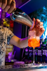 man hand bartender making sweet and sour refreshing Aperol Spritz cocktail on the bar counter