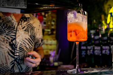 man hand bartender making sweet and sour refreshing Aperol Spritz cocktail on the bar counter