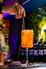 man hand bartender making sweet and sour refreshing Aperol Spritz cocktail on the bar counter