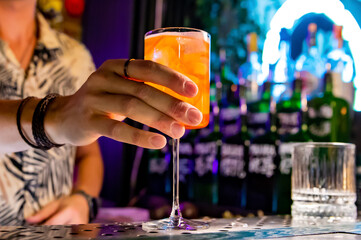 man hand bartender making sweet and sour refreshing Aperol Spritz cocktail on the bar counter
