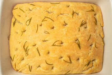 focaccia in a baking dish. Traditional Italian Focaccia with rosemary on a dark background. banner, menu, recipe place for text, top view