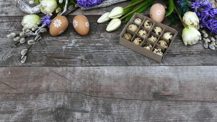 Ostern Hintergrund:  Blumen, Zweige, Wachteleier und Ostereier auf rustikalem Holz mit Platz für...