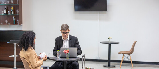 Two business workers are waiting and taking facility service at an exclusive airline lounge. Travelers get refreshment at a private lobby to be ready for their trip.