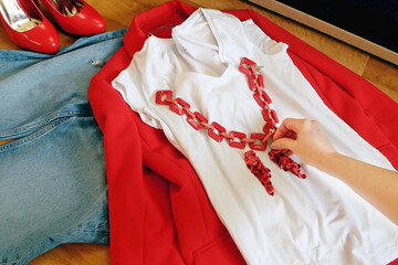 modern woman outfit with red jacket and jeans and white geometric bag, sorting out the wardrobe