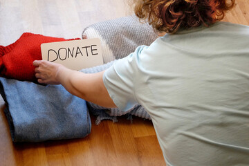 woman sorting clothes jeans, sweater, jackets for donation at home, second hand concept