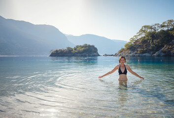 Summer lifestyle portrait of Happy traveller woman in black swimsuit enjoys her tropical beach vacation in Oludeniz Blue Lagoon Turkey.