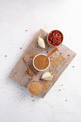 Mustard and pepper on a wooden board on a white background, top view.