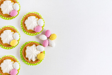 Five Easter tartlets decorated with sweets Easter eggs on a light background, close-up. Copy space. Easter delicious dessert.