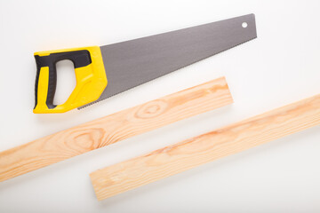 Hand saw and wooden planks on white table background. Closeup. Top down view.