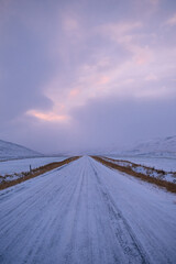 Snowy road leading to the horizon in Iceland at sunset