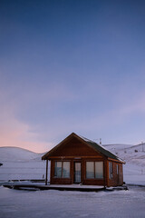 Isolated wooden cabin in the middle of snow at sunset in Iceland