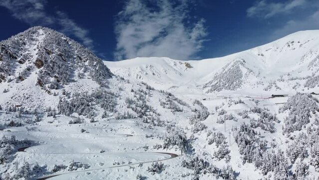 Vallter 2000 ski resort. Aerial winter landscape with winding road, snowy mountains. Ski station, cacations, travel and tourism concept. Setcases, Ripoll&eacute;s, Girona Pyrenees, Catalonia. 4k drone video.