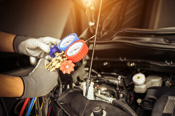 Hand of car mechanic technician use meter to check car air conditioner system heat problem and fix repairing and filling air refrigerant.