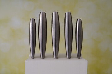 A set of metal knives on a white stand against a blurred background