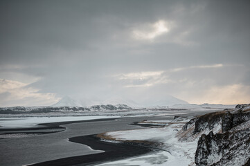 Snowy fjord landscape in Iceland with calm water and black beaches