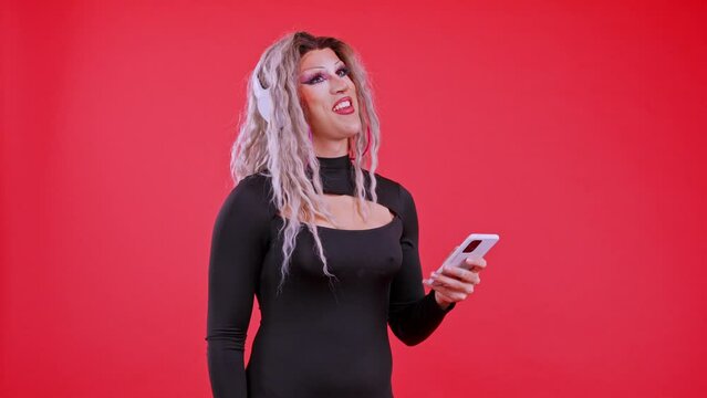 Drag queen man listening music with headphones and a mobile