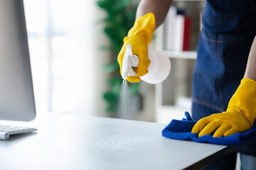 Person cleaning the room, cleaning staff is using cloth and spraying disinfectant to wipe the glass...