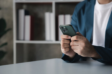Business man looking at financial information from a mobile phone, he is checking company financial documents, he is an executive of a startup company. Concept of financial management.