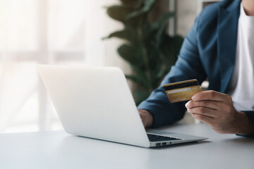 Person holding a credit card, uses a credit card to pay for goods and services online, the concept of using a credit card for online shopping, ordering goods and services on the website.