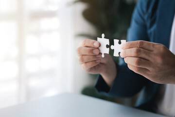 Man holding two jigsaw puzzles put together, business management concept and business risk management. Business solutions, success and strategy concept.