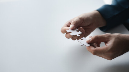 Man holding two jigsaw puzzles put together, business management concept and business risk management. Business solutions, success and strategy concept.