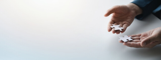 Man holding two jigsaw puzzles put together, business management concept and business risk management. Business solutions, success and strategy concept.