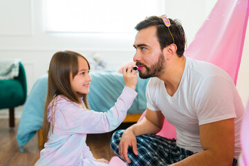 Attractive dad playing makeup with his daughter